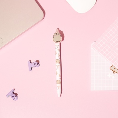 Caneta decorativa com topper de gato e clips roxos sobre fundo rosa.