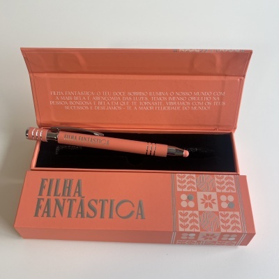 Caneta rosa dentro de caixa rosa com padrão floral e texto FILHA FANTASTICA