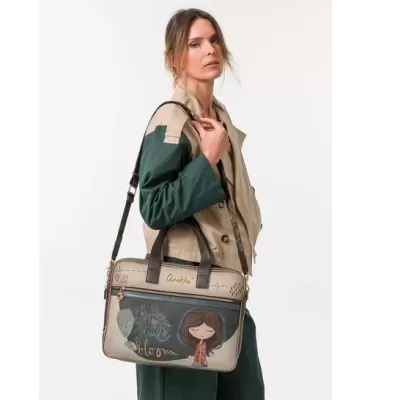 Mala de ombro com ilustração de menina e texto Sweet bloom, alças pretas, em modelo com casaco bege e verde