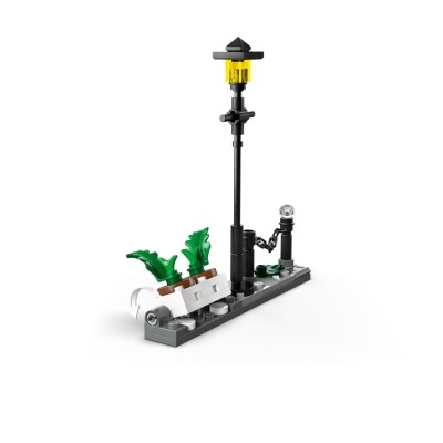 Miniatura de lampião preto com luz amarela e plantas em base cinza feita com peças de construção