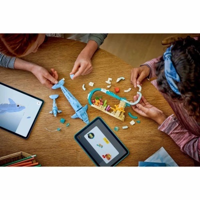 Crianças montando brinquedo de construção em forma de tubarão com tablets de instruções