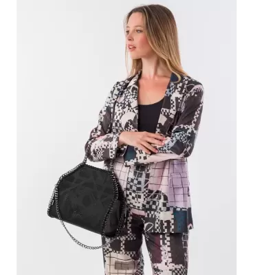 Mulher veste fato geométrico com mala preta de corrente