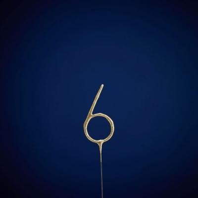 Vela dourada em forma de número 6 com fundo azul escuro