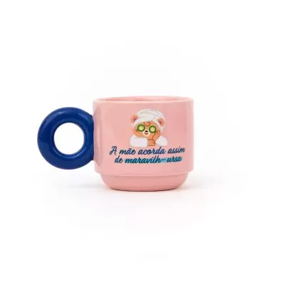 Caneca rosa com asa azul em forma de círculo e ilustração de urso com texto