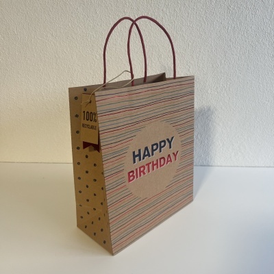Saco de papel castanho com texto 'HAPPY BIRTHDAY' e alças vermelhas