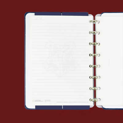 Caderno de argolas azul aberto com folhas pautadas sobre fundo vermelho