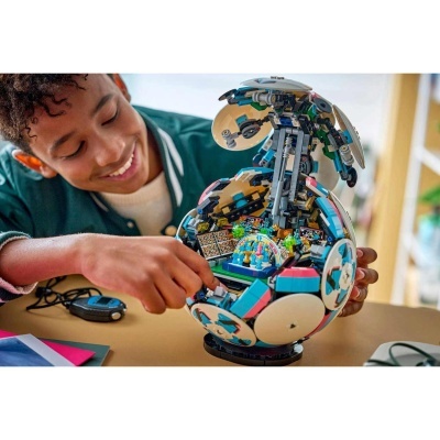 Brinquedo de construção tipo LEGO esférico com interior detalhado e colorido sendo manuseado por criança.