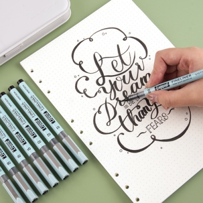 Marcadores fineliner líquidos azuis e cinza e caligrafia em papel pontilhado branco.