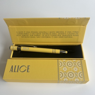 Caneta amarela em caixa amarela com detalhes dourados e texto em português sobre Alice