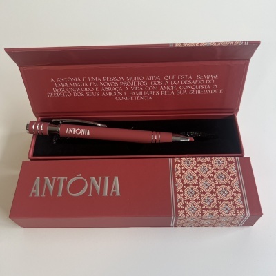 Caneta vermelha com caixa decorada e texto descritivo no interior da tampa