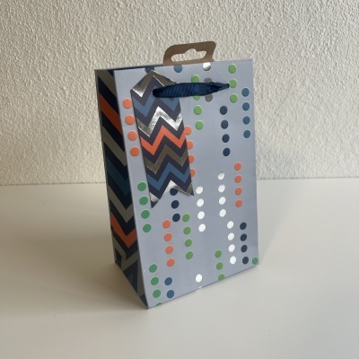 Saco de presente de papel cinza com padrão colorido e alça azul