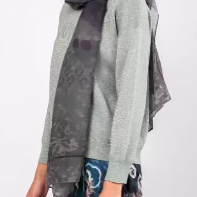 Pessoa com camisola cinza claro, lenço cinza escuro com padrão, saia padrão abstrato