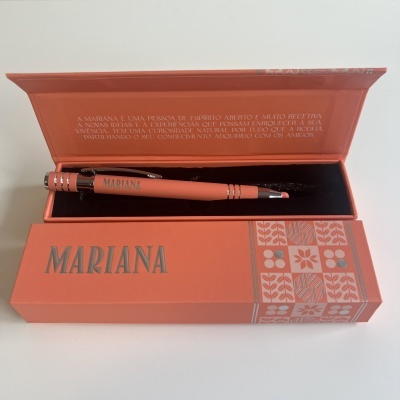 Caneta laranja com estojo e palavra MARIANA em destaque