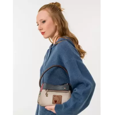 Mala pequena de senhora bege com alça castanha e desenho de gato, mostrada por mulher com camisola azul