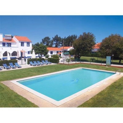 Piscina exterior retangular com espreguiçadeiras e edifícios ao fundo