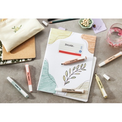 Caderno decorado com marcadores pastéis e estojo de tecido sobre mesa cinzenta