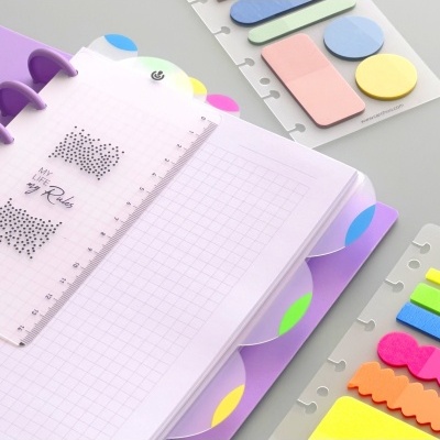 Caderno quadriculado com separadores coloridos, régua transparente e notas adesivas coloridas
