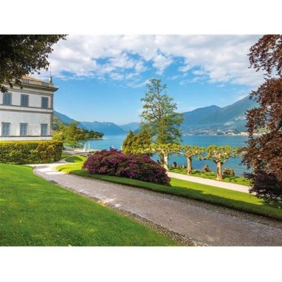 caminho de cascalho com relva, arbustos e árvores junto a lago e edifício