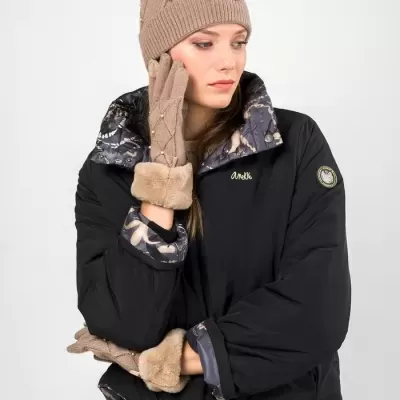 Mulher com casaco preto, luvas bege com pelo e gorro bege com pompom