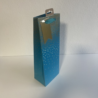 Sacola de papel azul com pontos prateados e etiqueta dourada