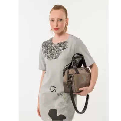 Mulher com vestido cinzento claro e mala castanha com alças pretas