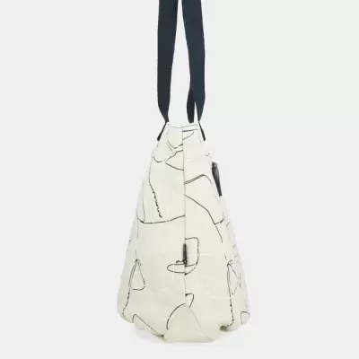 Mala de ombro bege com padrão de linhas abstratas e alças pretas vista de perfil