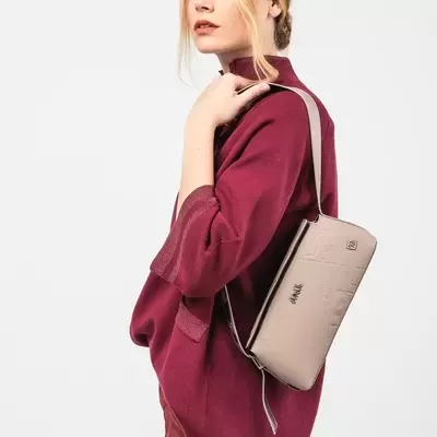 Mulher com camisola vinho e bolsa bege com texto ANAA