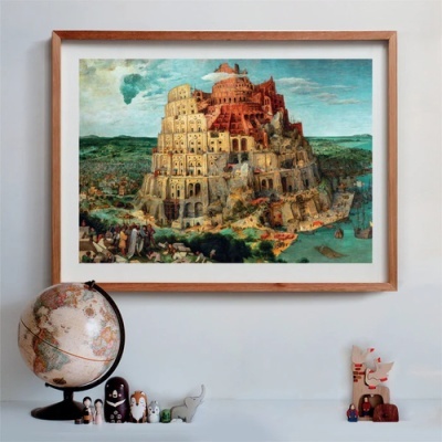 Quadro com pintura da Torre de Babel em moldura de madeira sobre parede branca com globo e miniaturas decorativas em superfície branca