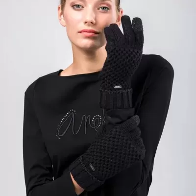 Mulher com luvas pretas trançadas e camisa preta com detalhe brilhante