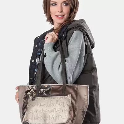 Mulher com colete preto, camisola cinza e bolsa bege castanha com texto manuscrito