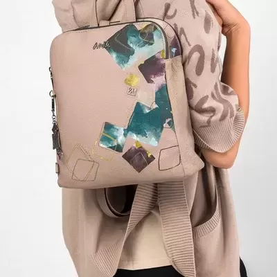 Mochila bege com padrão artístico usado por mulher com casaco bege