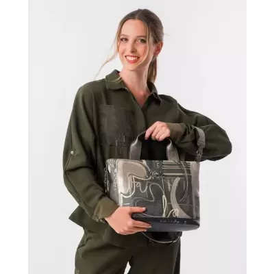 Mulher com camisa e calças verdes segurando bolsa grande com padrão abstrato