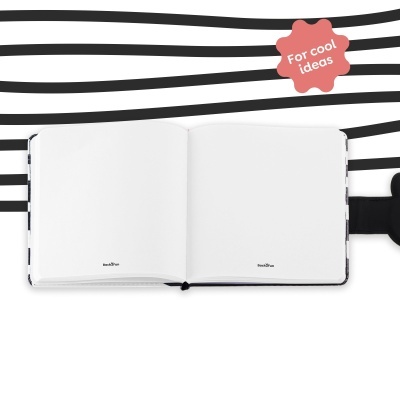 Caderno aberto com páginas em branco e capa com fecho preto em fundo riscado