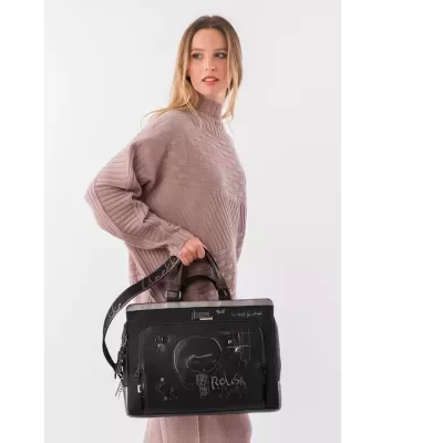 Mulher com camisola rosa clara de malha segurando mala preta decorada com desenhos e texto