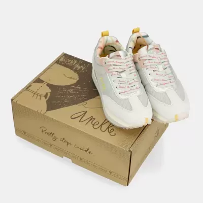 Sapatilhas brancas com detalhes amarelos e rosa sobre caixa castanha Anekke