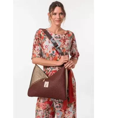 Mala castanha e bege com textura e alça larga usada por mulher com vestido floral