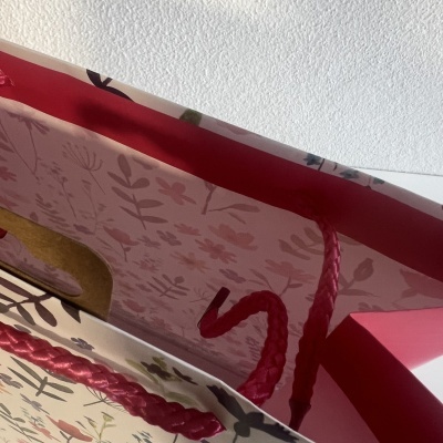 Saco de papel decorativo com padrão floral e alças trançadas rosa