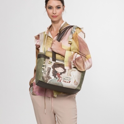 Bolsa de senhora com padrão ilustrado em verde, bege e castanho, com mulher a segurar a bolsa e roupa casual colorida