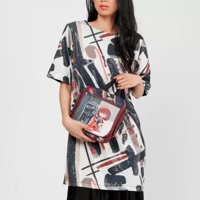 Mulher com túnica estampada abstrata e calças pretas segura mala pequena com imagem de personagem animado