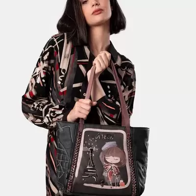 Mulher com vestido a segurar mala preta decorada com imagem da Torre Eiffel e rapariga