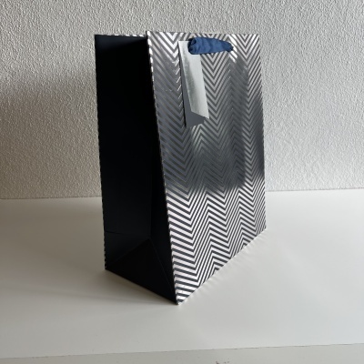 Saco de papel prateado com padrão zig-zag e alças azuis