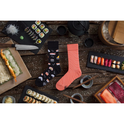 Meias coloridas com padrão de sushi sobre mesa com comida japonesa.