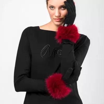 Mulher com luvas pretas com punhos vermelhos felpudos e camisa preta com texto em strass