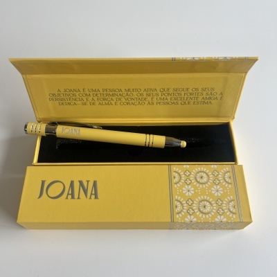 Caneta dourada com nome JOANA dentro de caixa amarela decorada