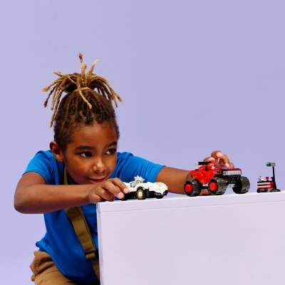 Criança brinca com carros LEGO em superfície branca