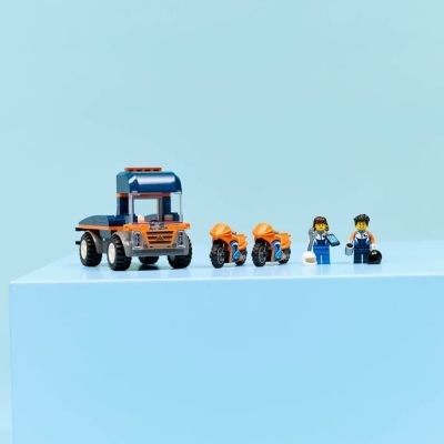 Conjunto de brinquedo com camião, motos e mini-figuras sobre superfície azul clara