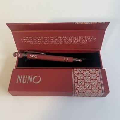 Caneta vermelha com caixa vermelha decorada e texto em português