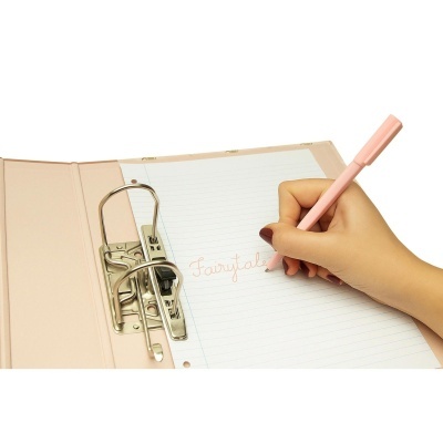 Caderno rosa claro com anilhas metálicas e papel pautado, mão escreve Fairytale com caneta rosa.