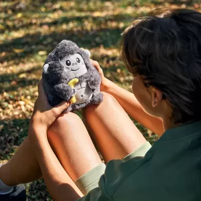 Pessoa a segurar peluche de gorila cinzento com banana amarela