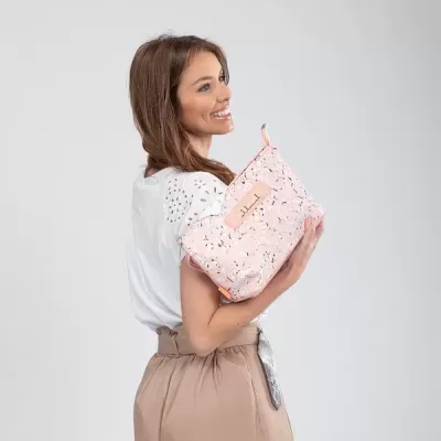Mulher segurando bolsa rosa claro com padrão floral em fundo cinza claro
